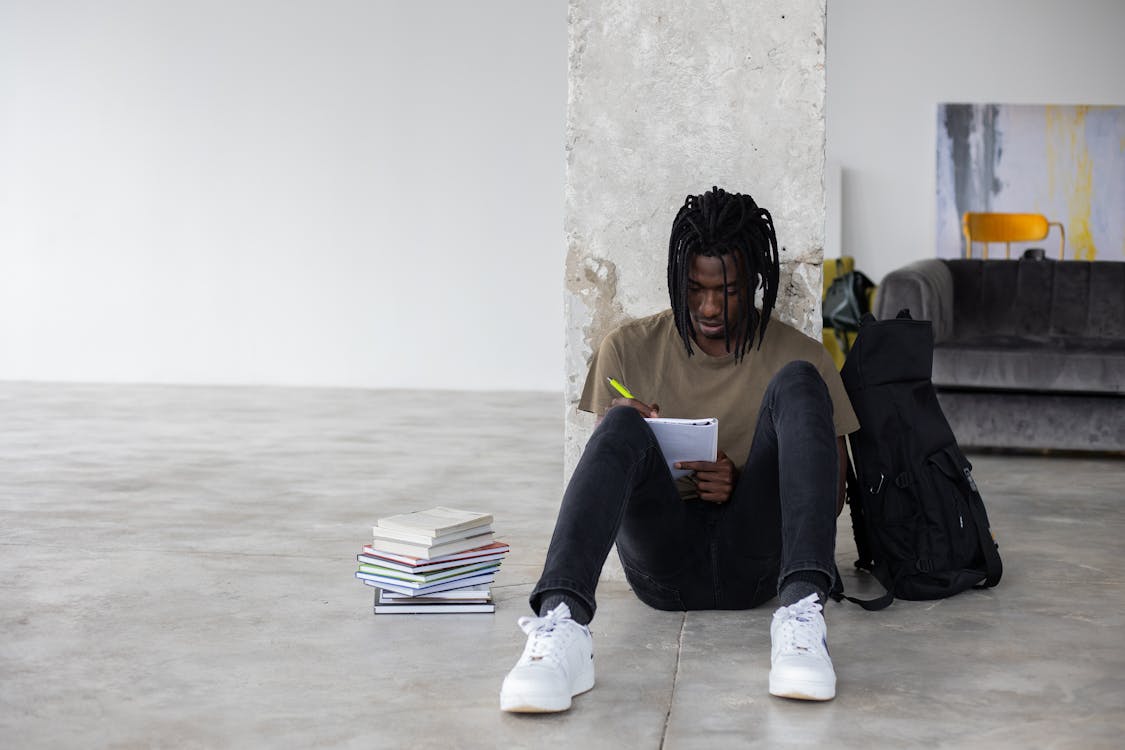 Free Black man writing in notebook while doing homework Stock Photo